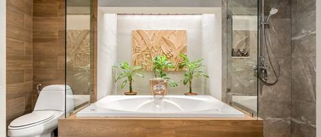A modern bathroom with a glass-enclosed shower, a freestanding bathtub, and a toilet.