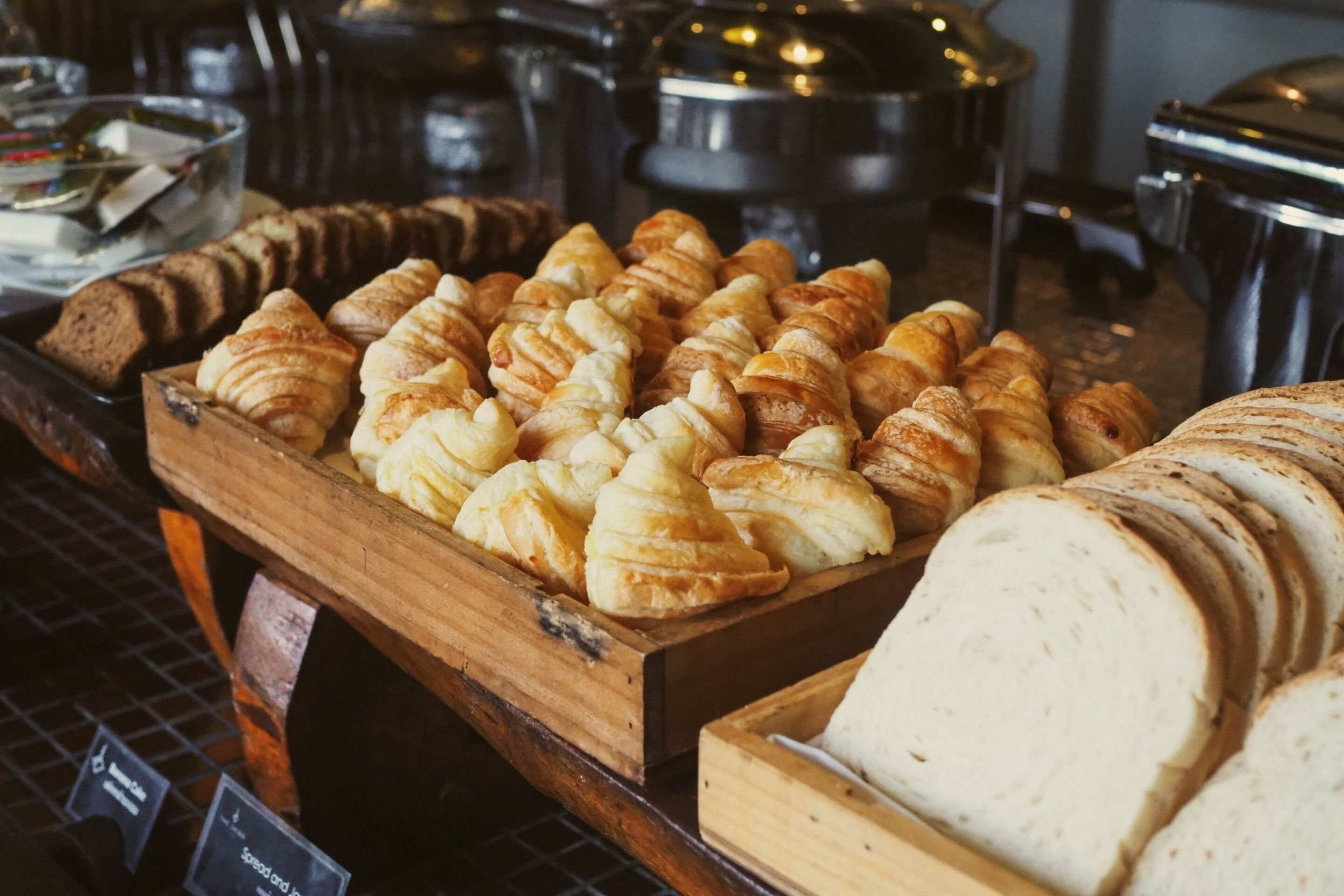 A variety of baked goods, including croissants and bread, displayed on wooden trays.