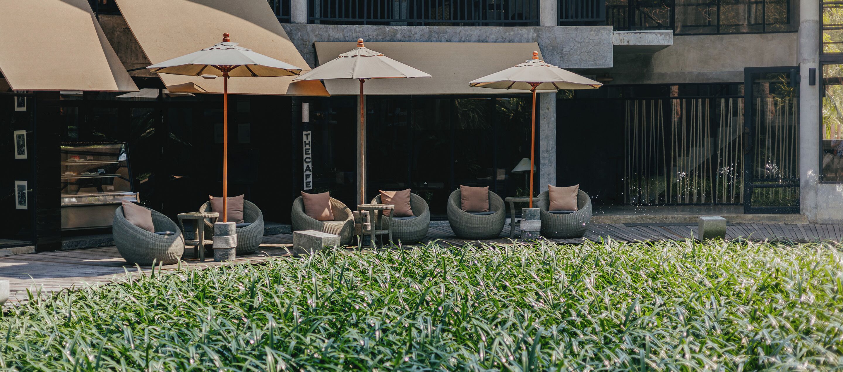 Outdoor seating with umbrellas, a garden area, and a building with a modern design.