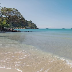 Enjoy a tranquil beach experience with turquoise waters and gentle waves lapping onto the sandy shore.