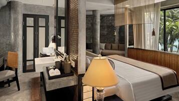 Une chambre d’hôtel moderne dotée d’un grand lit, d’un coin salon, d’une salle de bain avec un lavabo et un miroir, et offrant une vue sur les palmiers.
