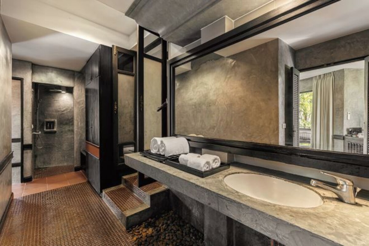 Un baño moderno con un espejo grande, un lavamanos y una zona de ducha.