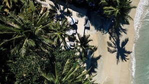 An aerial view of a beachside resort with palm trees, beach chairs, and umbrellas. - The Dewa Koh Chang (Ko Chang)