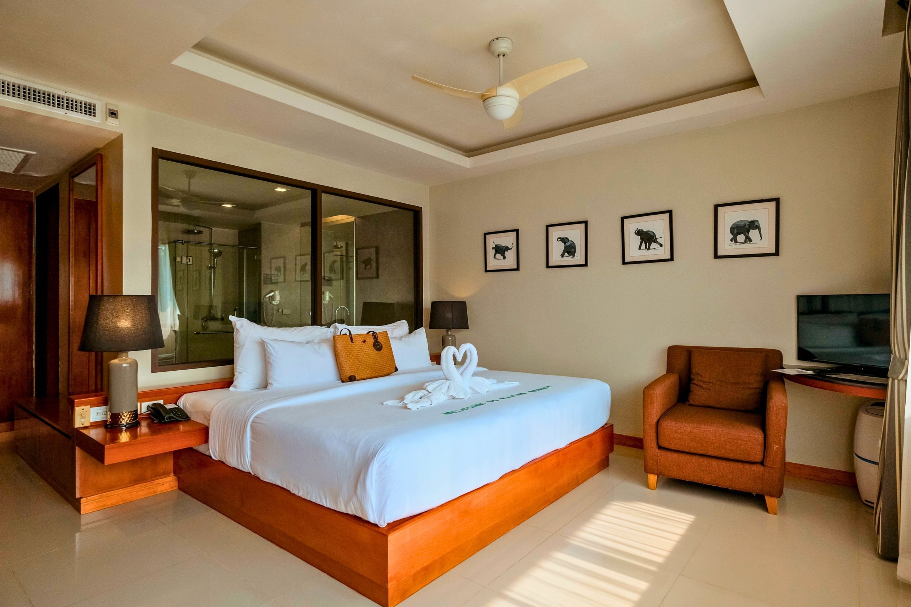 Habitación de hotel con una cama grande, un área de descanso con una butaca, televisión y fotografías enmarcadas de animales en la pared.