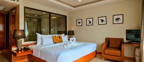 Habitación de hotel con una cama grande, un área de descanso con una butaca, televisión y fotografías enmarcadas de animales en la pared.