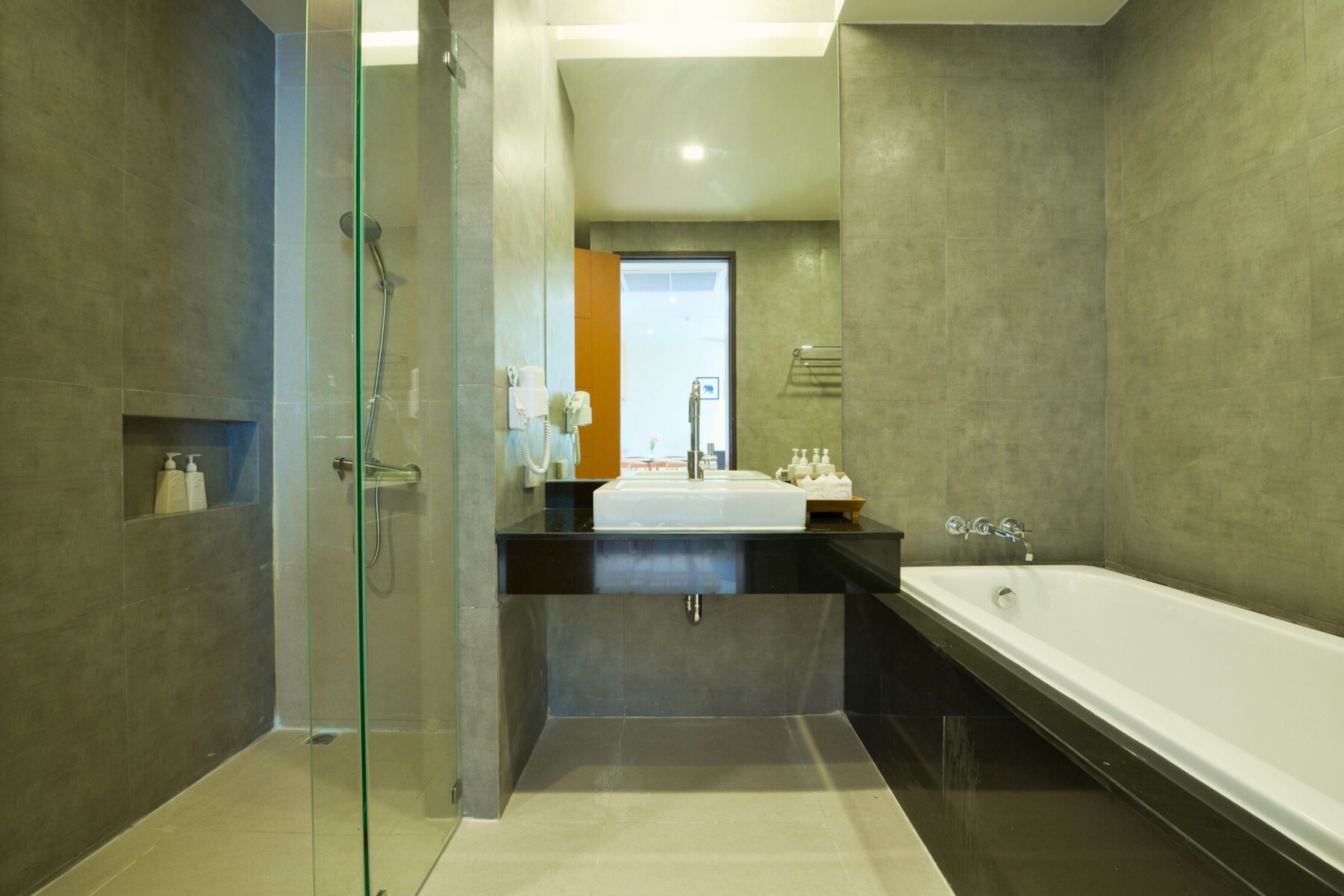 Un baño moderno con ducha envuelta en vidrio, una bañera grande y un tocador con lavamanos.