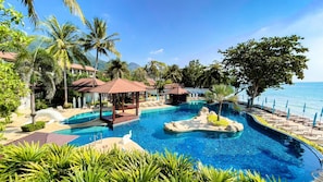 A resort pool with a gazebo, palm trees, and a view of the ocean.
