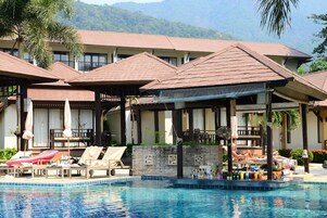 Ein Hotel mit Schwimmbad, Liegestühlen und Sonnenschirmen.