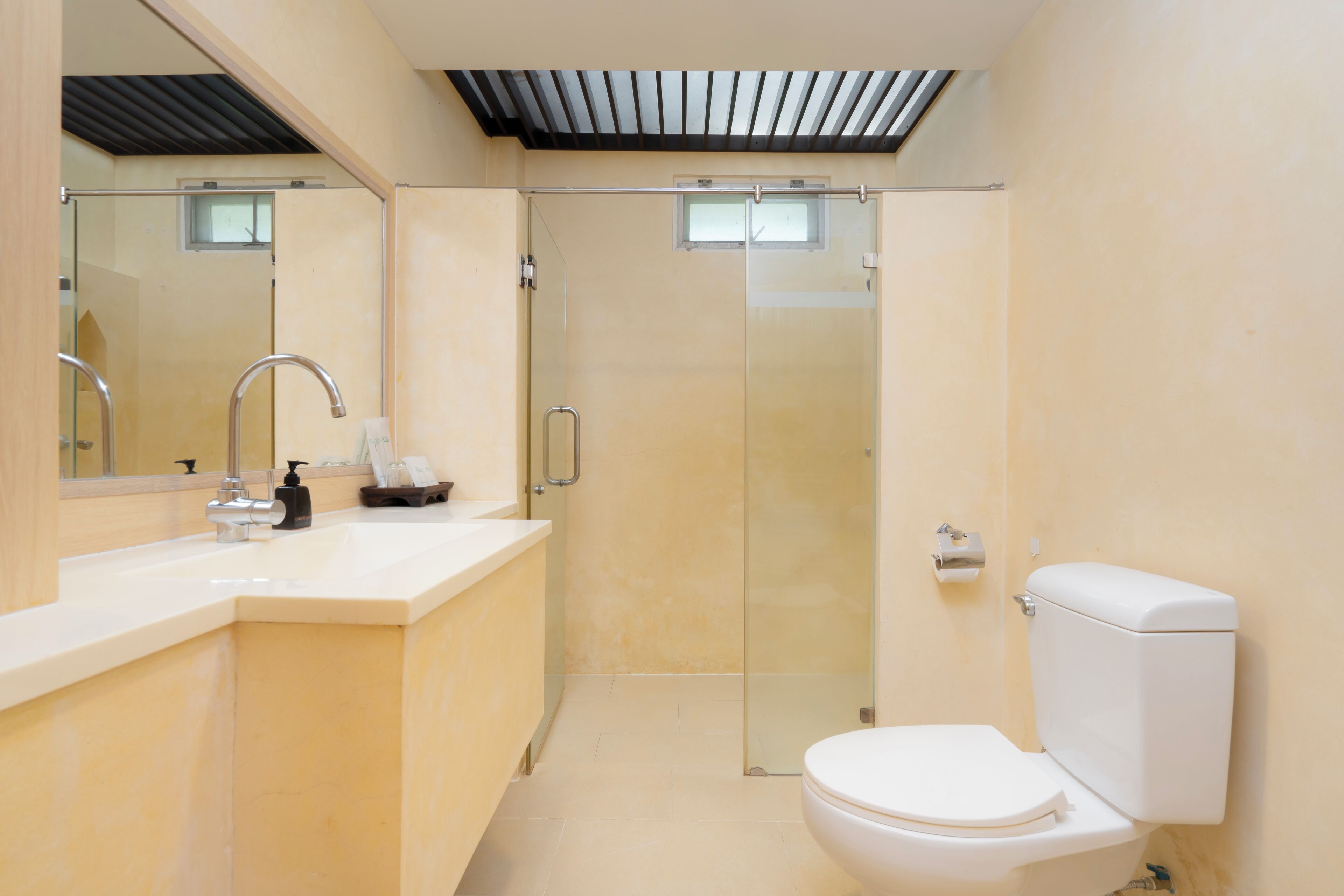 A modern bathroom with a glass shower enclosure, a white toilet, and a sink with a mirror above it.