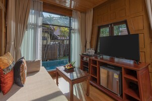 Ein Wohnzimmer mit Sofa, Couchtisch, Fernseher und kleinem Kühlschrank.