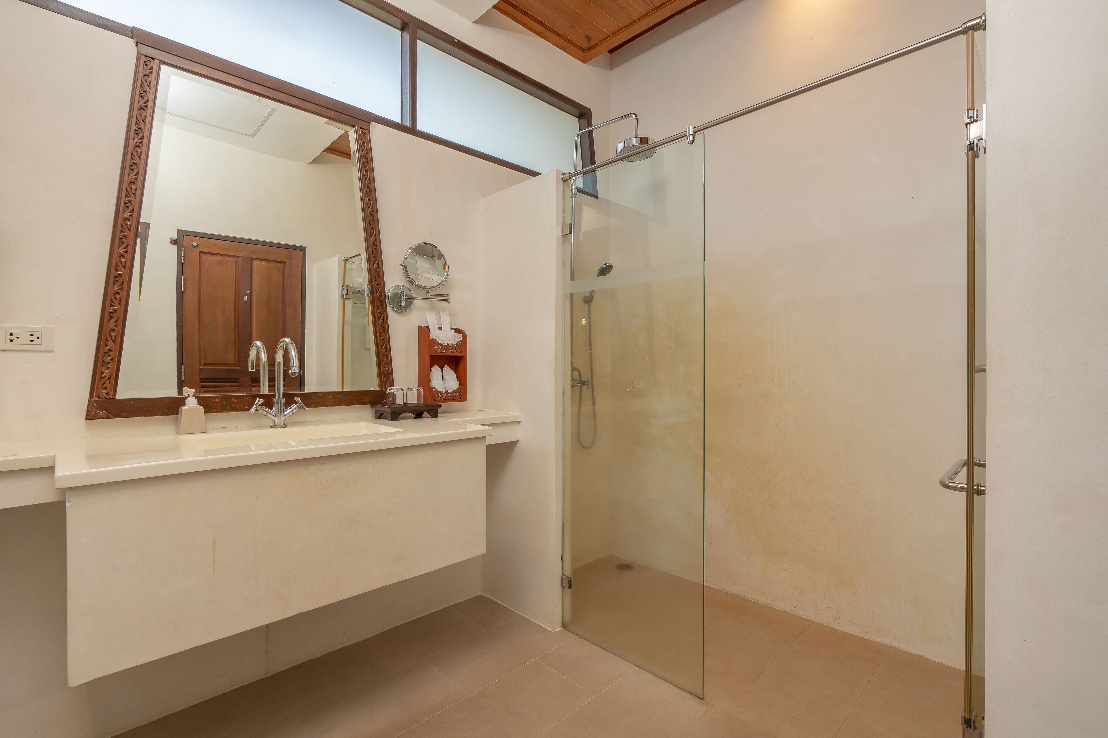 Une salle de bain dotée d’une douche à parois de verre, d’une porte en bois et d’un grand miroir au-dessus du lavabo.