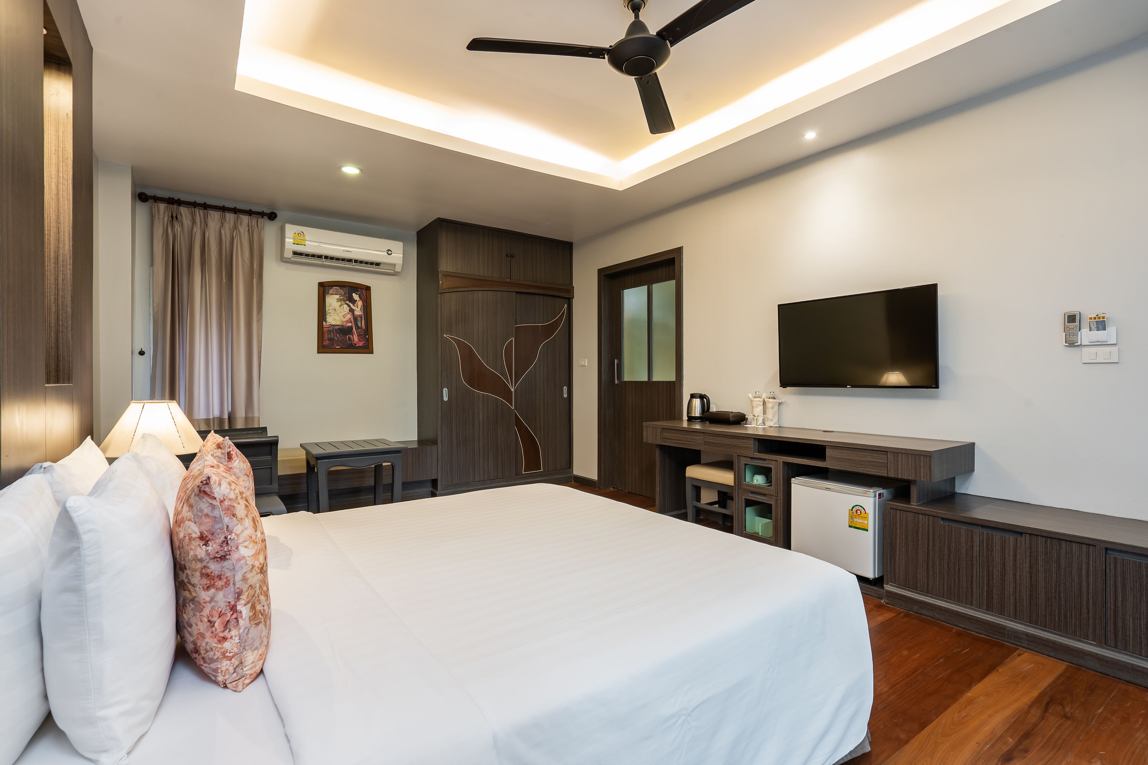 A hotel room with a bed, a desk, a television, and a ceiling fan.