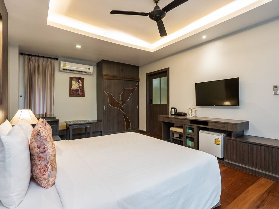 A hotel room with a bed, a desk, a television, and a ceiling fan.