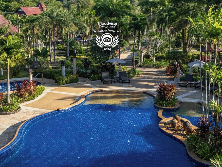 Zona de piscina en un resort con jacuzzi, sillas de descanso y jardines tropicales.