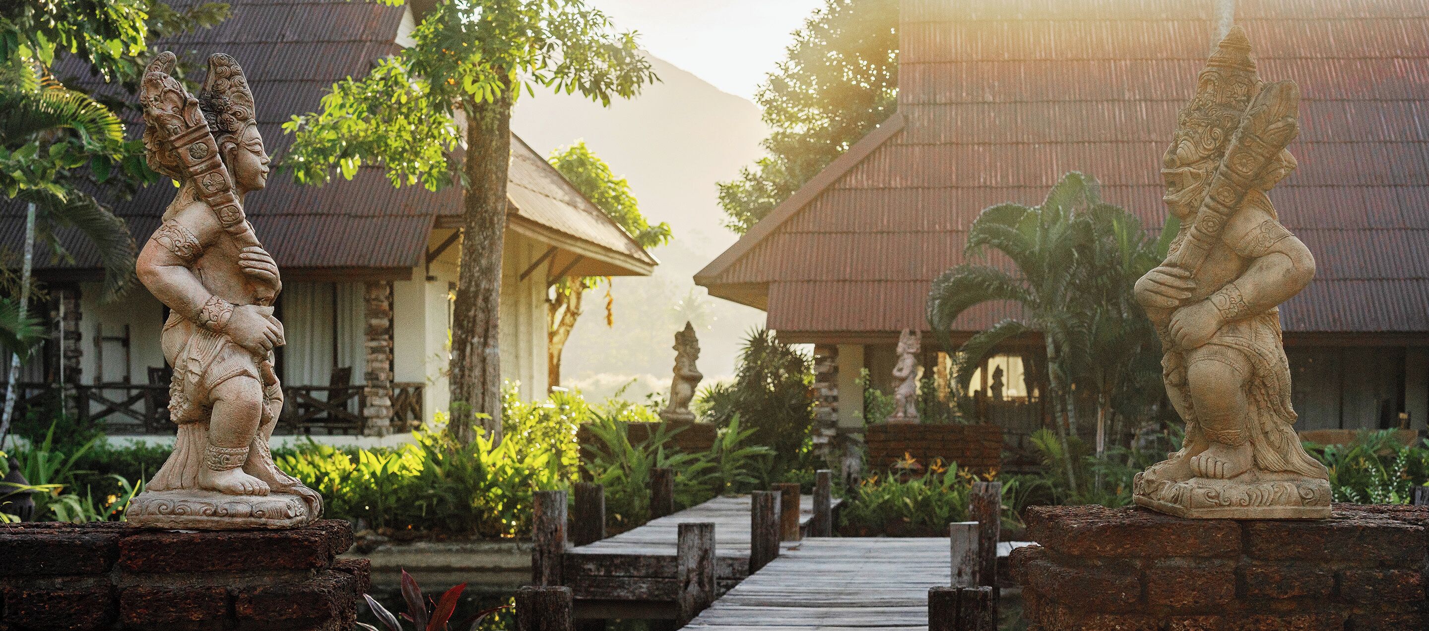 A pathway leading to traditional-style buildings with intricate stone statues at the entrance.