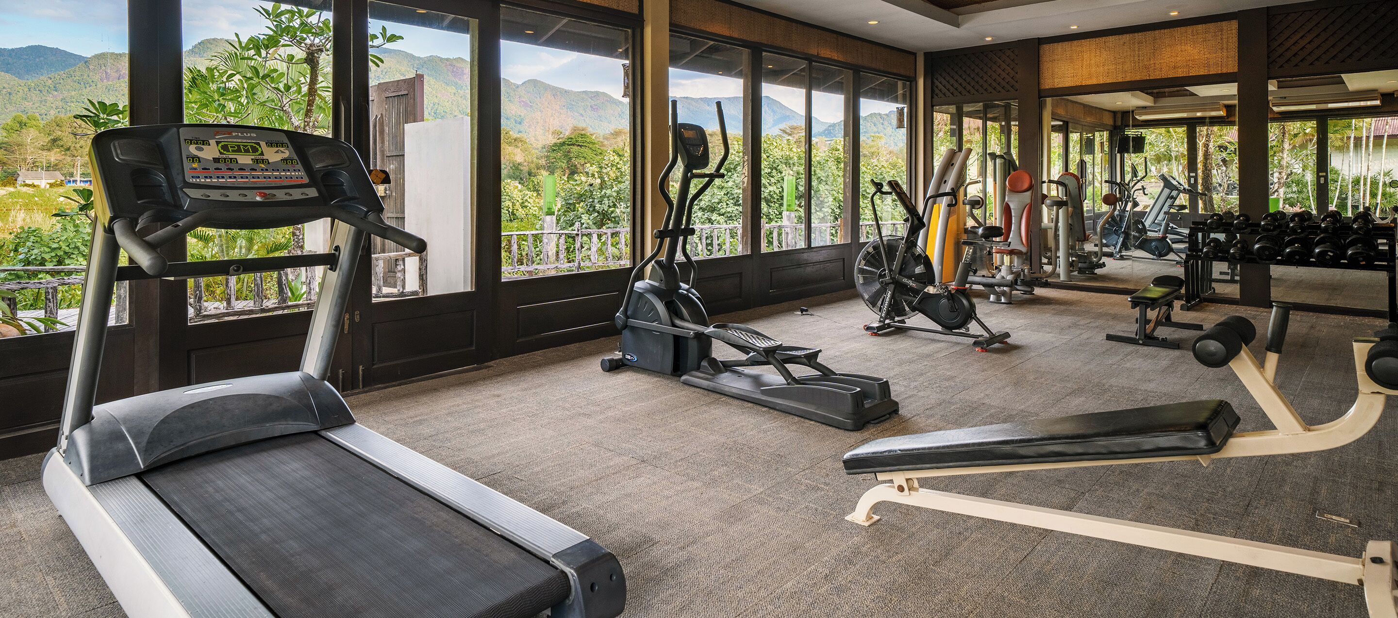 A gym with cardio machines, weight equipment, and a view of mountains.