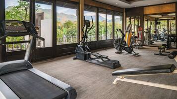 A gym with cardio machines, weight equipment, and a view of mountains.