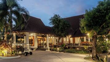 A hotel with a reception area, outdoor seating, and a well-lit entrance.