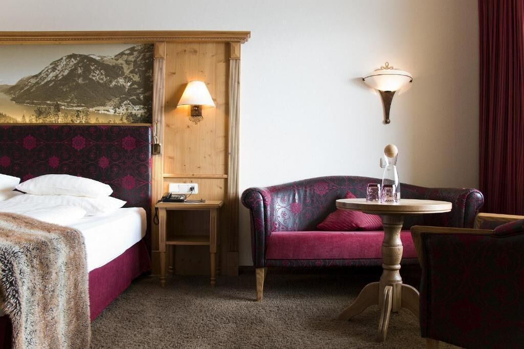 Una camera d'albergo con un letto, un tavolino, un divano e una lampada a parete.