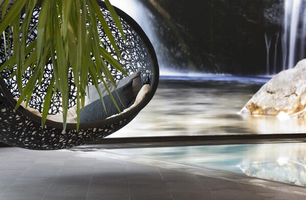 A modern indoor setting with a hanging chair, a waterfall view, and a tiled floor. - Hotel Post Am See (Eben am Achensee)