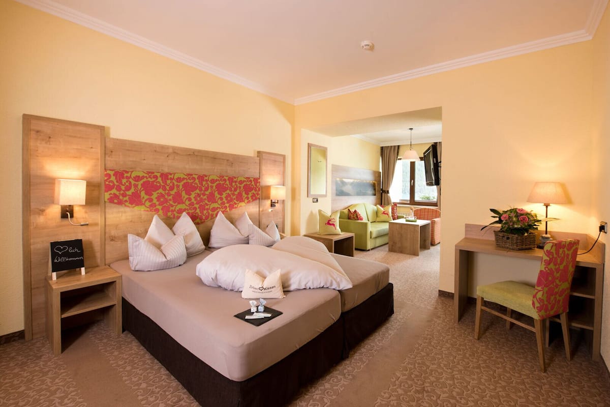 Ein Hotelzimmer mit einem großen Bett, einem Schreibtisch, einem Sessel, einer Couch und einem Fernseher.