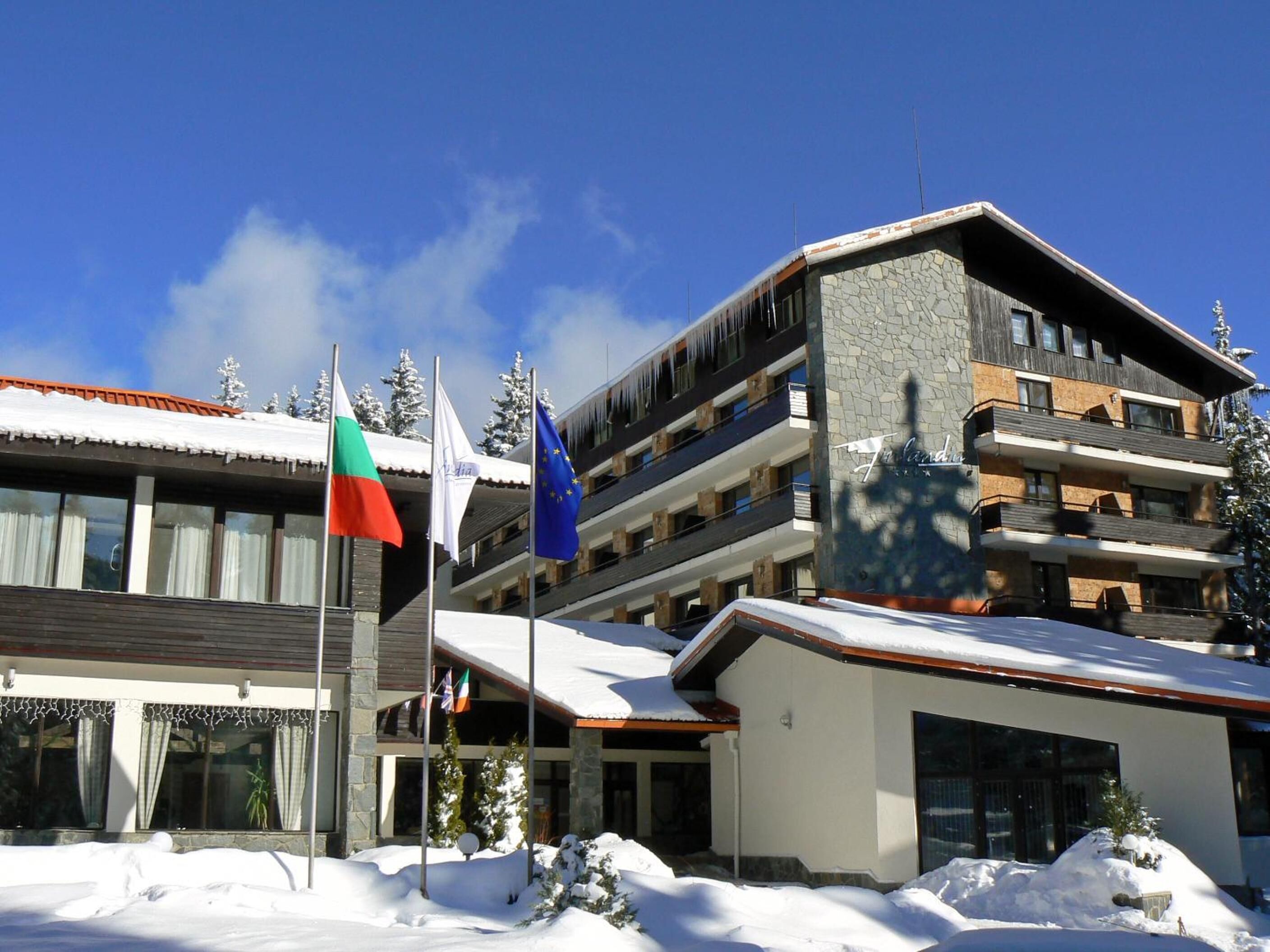 Un hotel de varios pisos con fachada de piedra y balcones, rodeado de nieve.