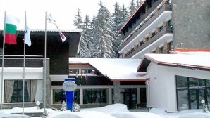 Un hotel con estacionamiento cubierto de nieve y un edificio de varios pisos con techo rojo.
