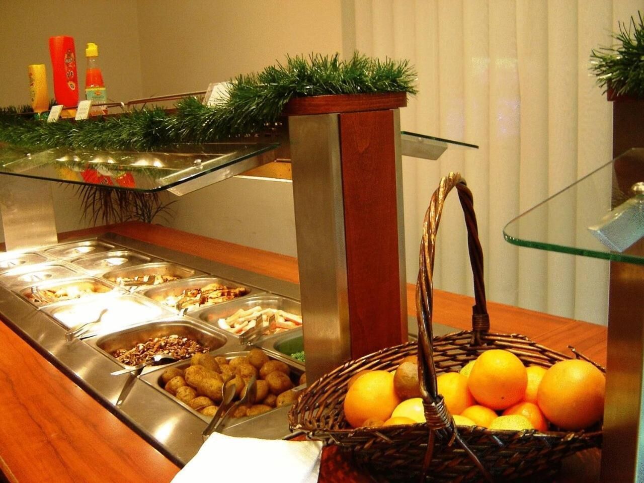 A buffet area with various food options and a basket of oranges.