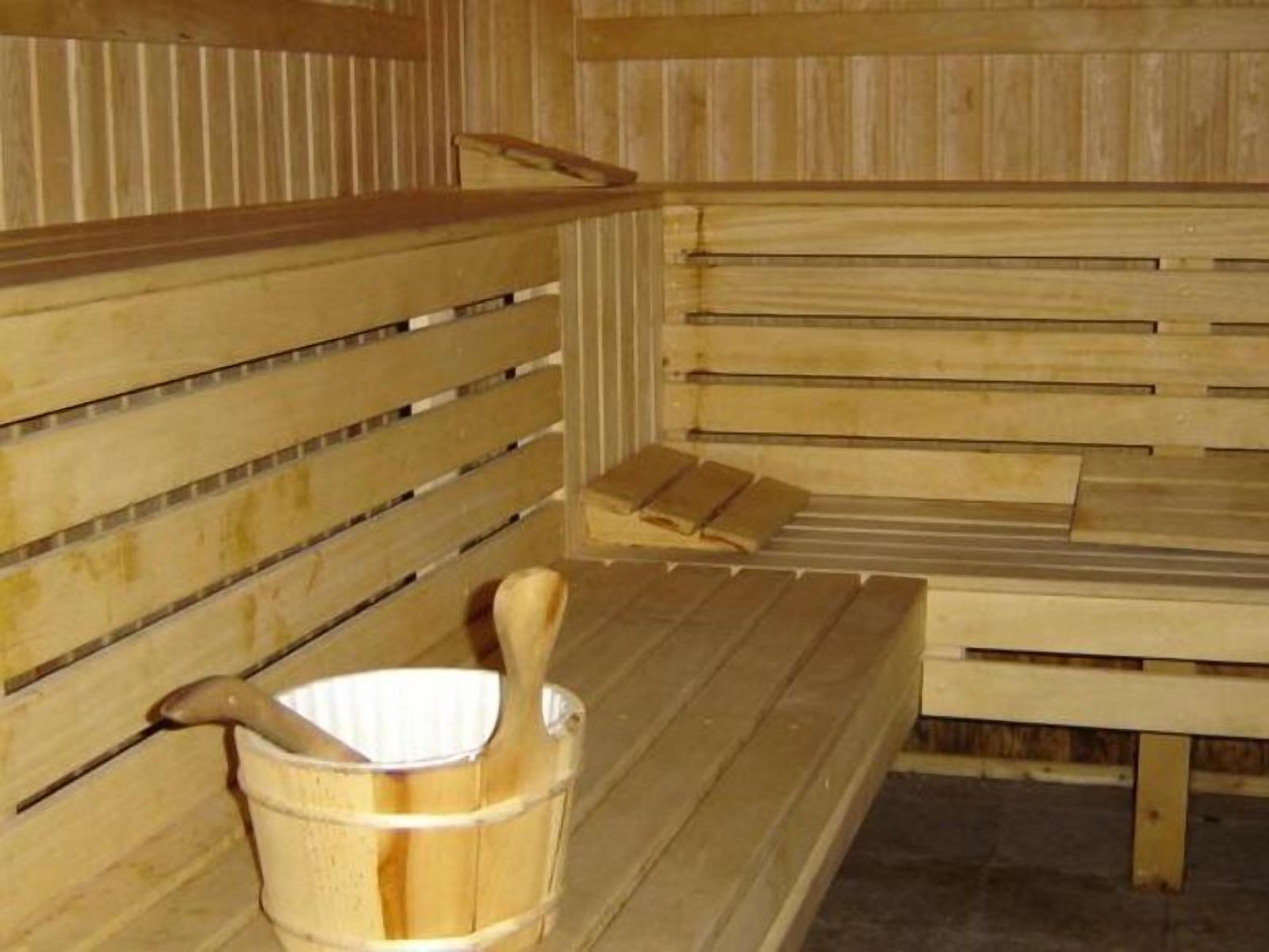 Eine Holzsauna mit Bänken und einem Holzeimer.