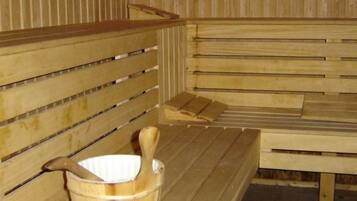 Eine Holzsauna mit Bänken und einem Holzeimer.