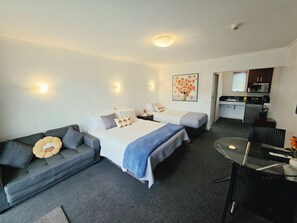 Une chambre d’hôtel avec deux lits, un canapé, une table à manger et une kitchenette.