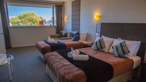 Een hotelkamer met twee bedden, een glazen tafel en uitzicht op de stad.