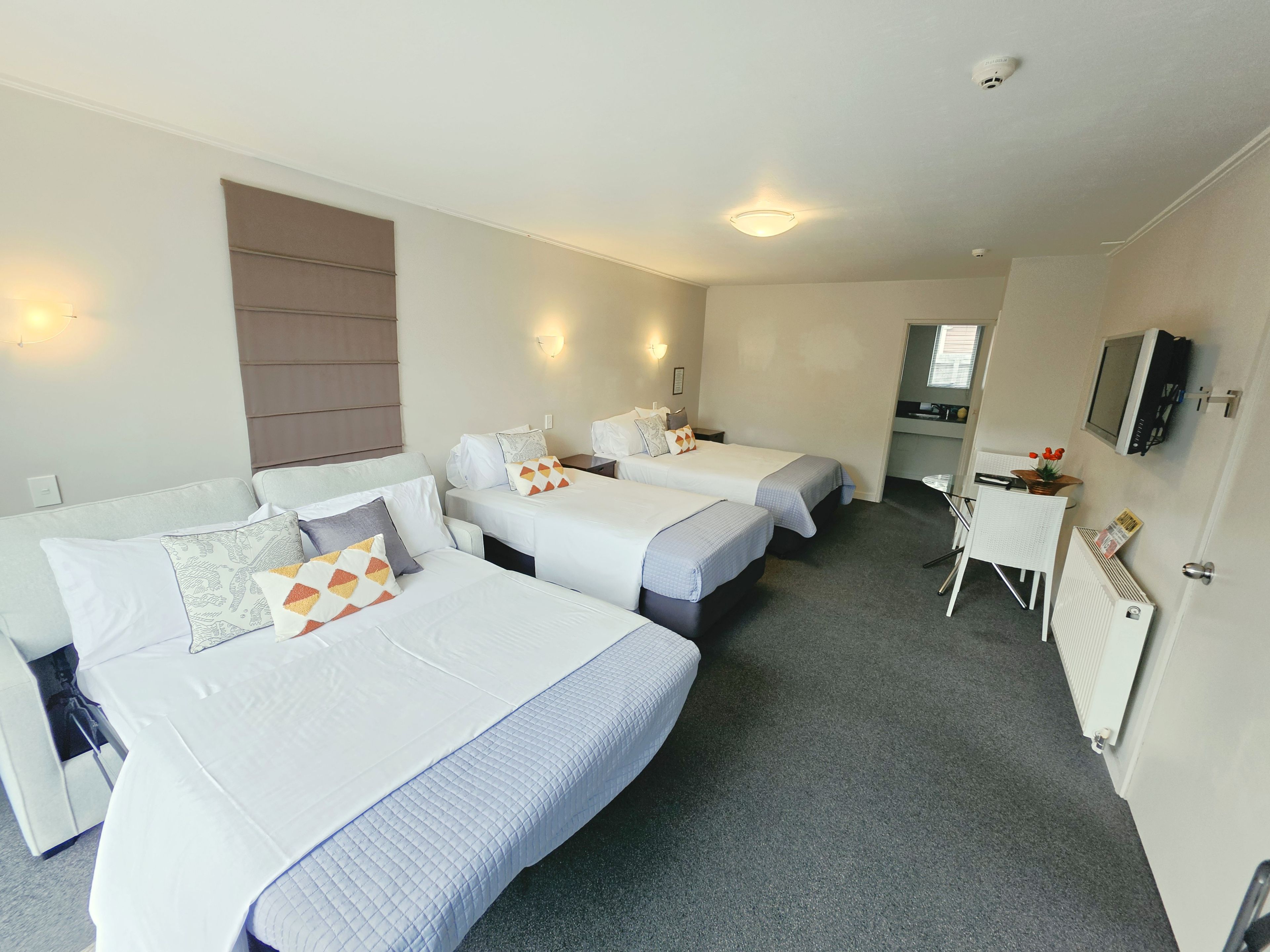 Ett hotellrum med två separata sängar, en soffa, ett skrivbord och en tv.