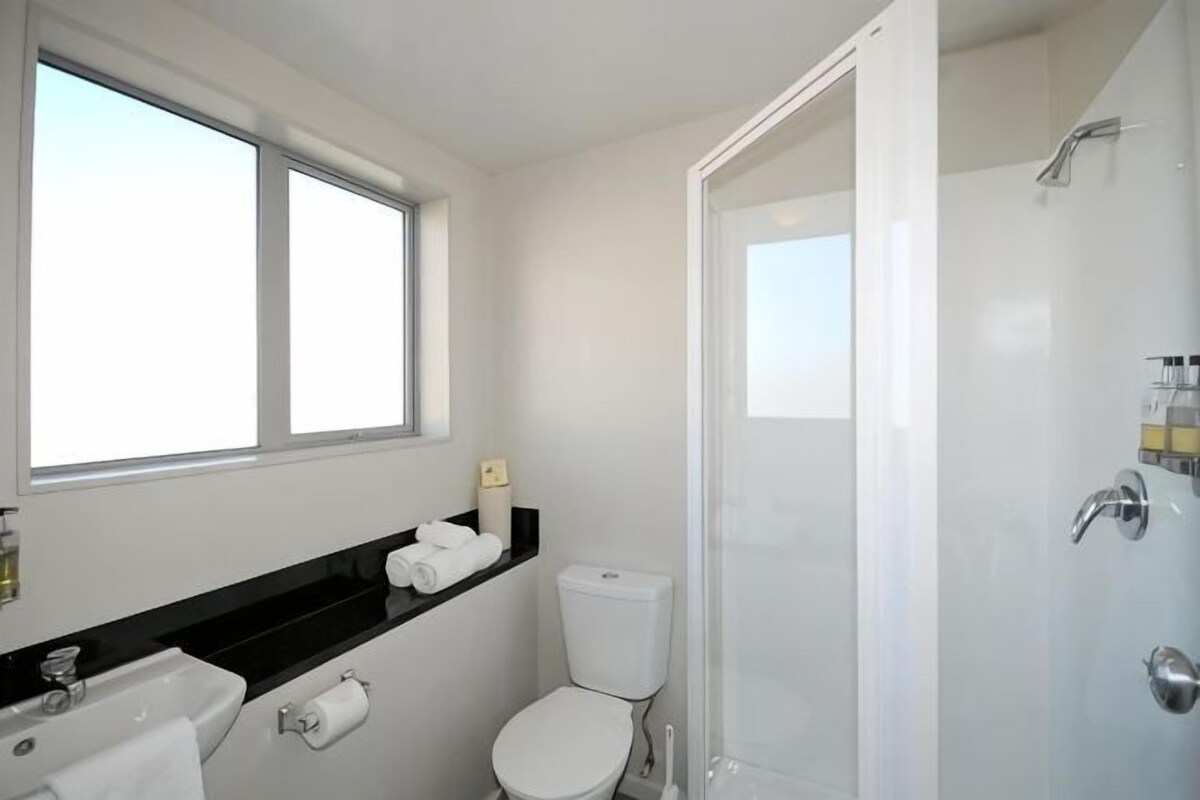 Une salle de bain avec des toilettes, un lavabo et une douche.