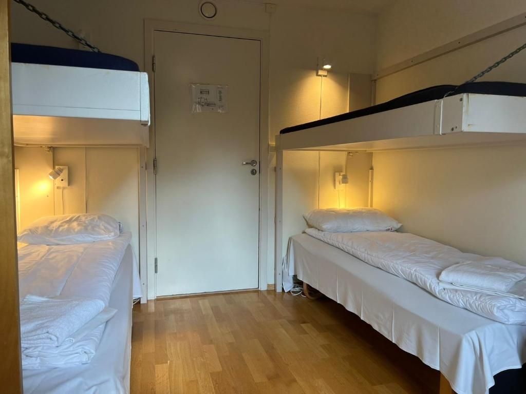Une chambre de dortoir avec des lits superposés, une porte et un luminaire.