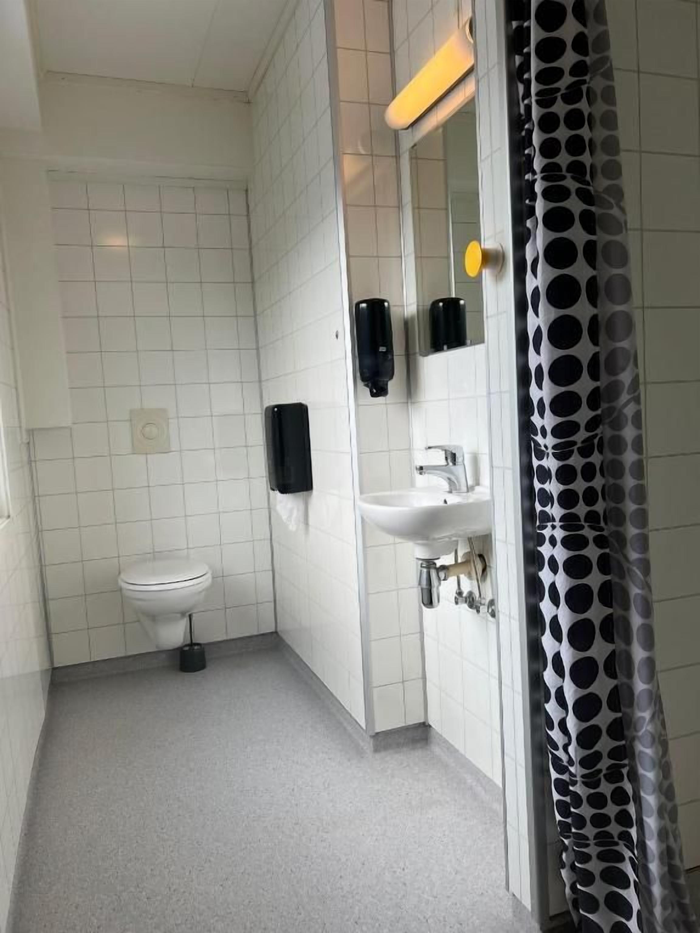 A small, clean bathroom with a toilet, sink, and hand dryer.