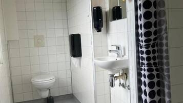 A small, clean bathroom with a toilet, sink, and hand dryer.