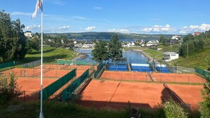 A tennis court with a flagpole and a view of a town and lake in the background. - Hovdetun - Gjøvik Vandrerhjem - Hostel (Gjovik)