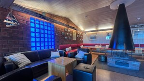 A modern lounge area with leather seating, a wooden table, and a unique black conical light fixture. - Hovdetun - Gjøvik Vandrerhjem - Hostel (Gjovik)