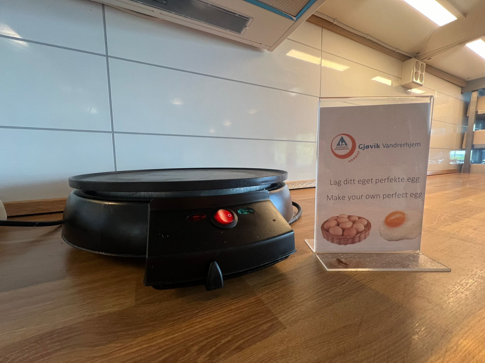 Cucina con piano cottura elettrico moderno e un cartello che pubblicizza un corso di cucina.