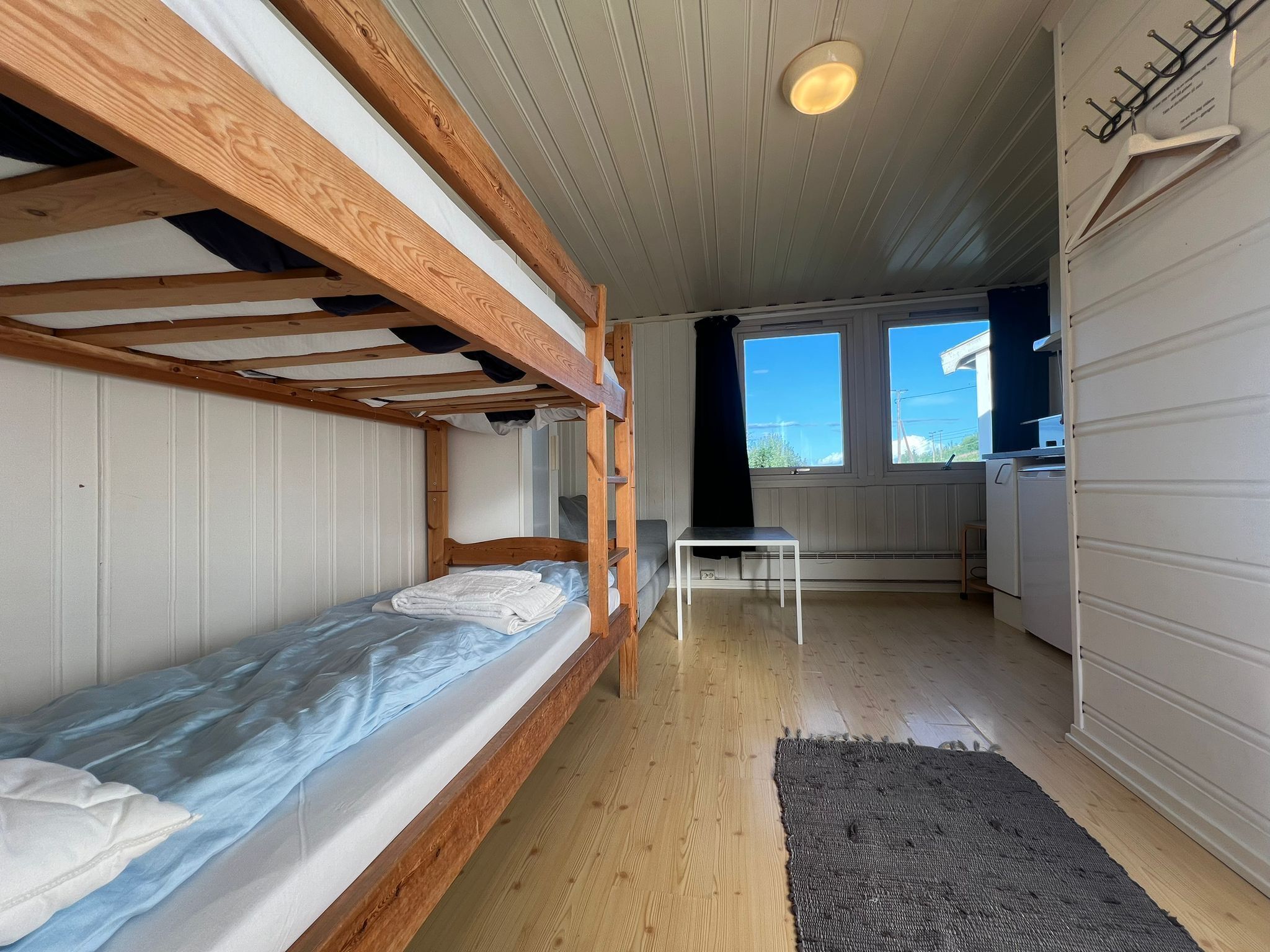 A compact room with bunk beds, a small table, and a kitchen area.