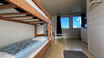 A compact room with bunk beds, a small table, and a kitchen area.