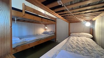 A bunk bed room with wooden beams, a single bed, and a nightstand.