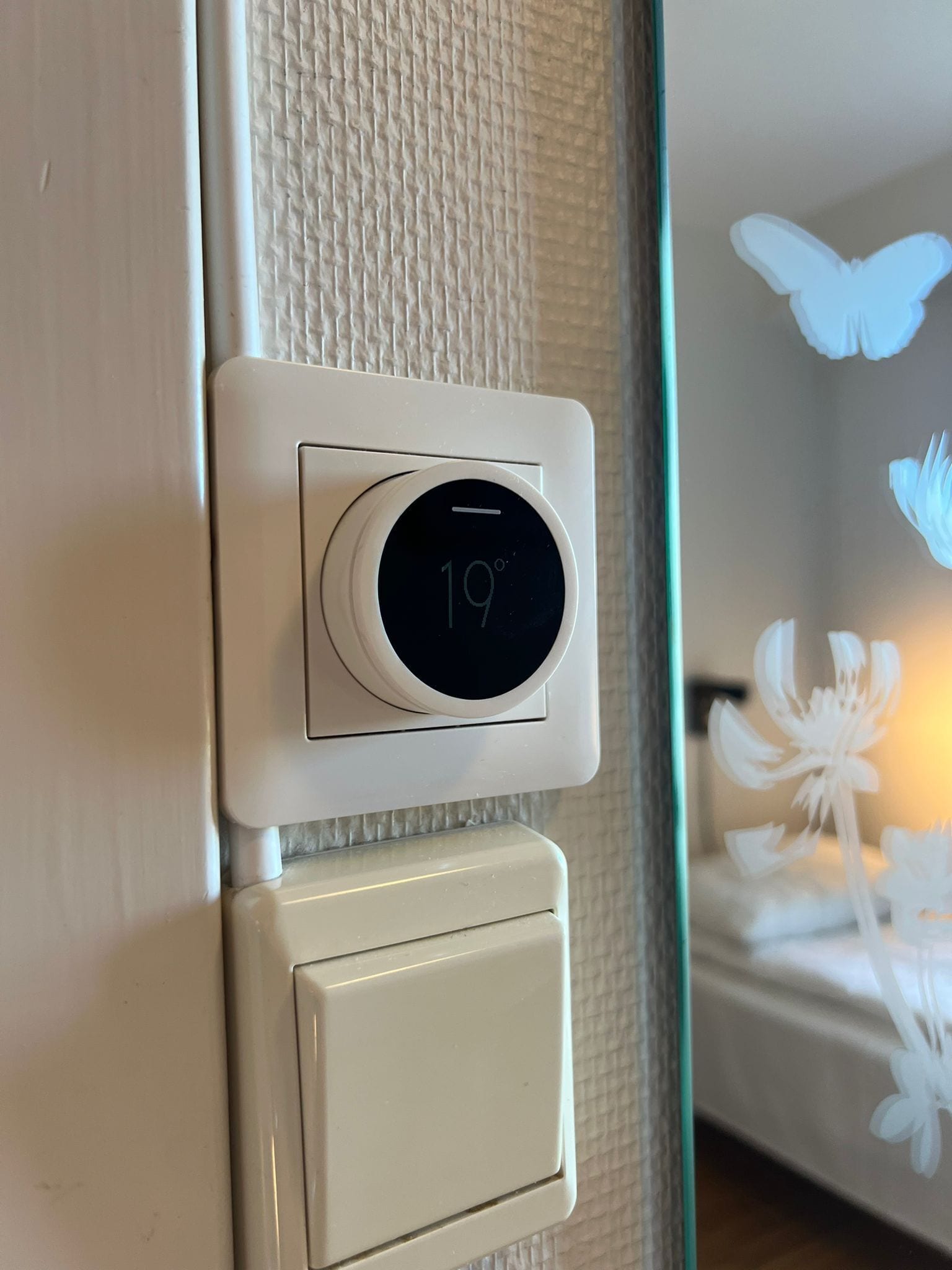 Termostat med digitalt display der viser 19 grader Celsius.