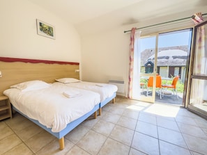 Une chambre d’hôtel avec deux lits, une grande fenêtre donnant sur l’extérieur et une petite table avec des chaises.