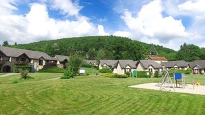 Une rangée de chalets, avec une pelouse verdoyante et une aire de jeux au premier plan.