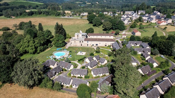 Vue aérienne d’un quartier résidentiel avec des maisons, une piscine et un grand immeuble doté d’une tour.