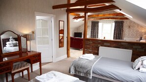 A bedroom with two beds, a wooden dresser, a mirror, and a brick wall. - Hundith Hill Hotel (Cockermouth)