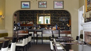 A bar area with a mirrored wall, bar stools, and a variety of bottles. - Hundith Hill Hotel (Cockermouth)