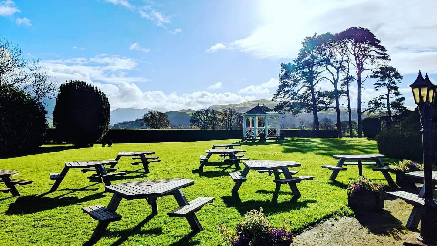 A grassy outdoor area with picnic tables and a gazebo.